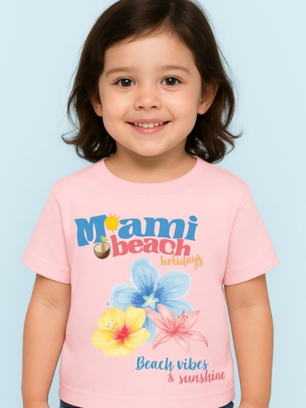 Pink kids’ t-shirt with Miami Beach Holidays floral design and “Beach vibes & sunshine” print.
